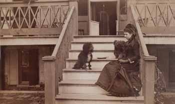 Miss Langdon seated with two dogs on steps of piazza Photograph